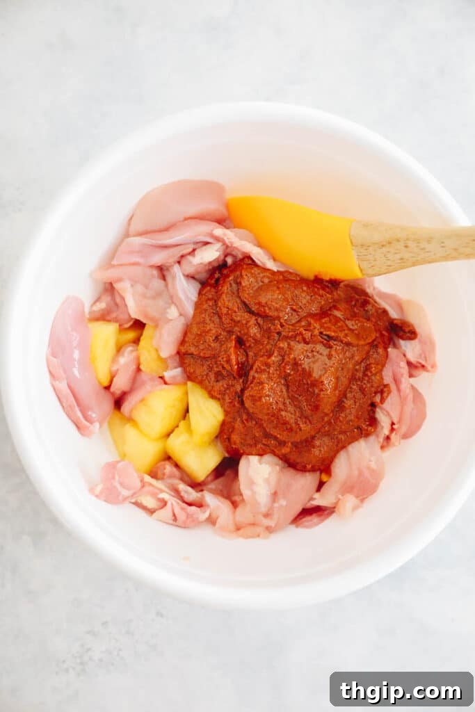 Achiote-Spiced Chicken Pastor 5 chicken marinating with pineapple and sauce in a bowl.