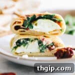 Up close image of spinach feta wrap stacked on top of each other on a white plate, perfect for sharing.