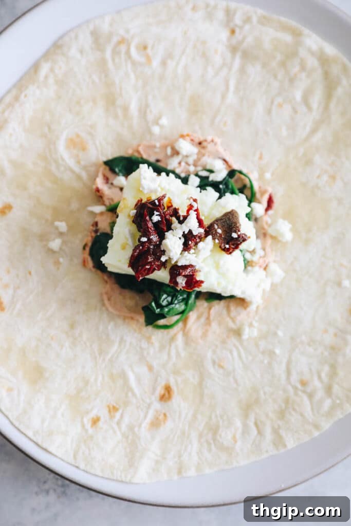 The Perfect Homemade Spinach Feta Breakfast Wrap 6 Assembling the spinach feta wrap with layers of ingredients.