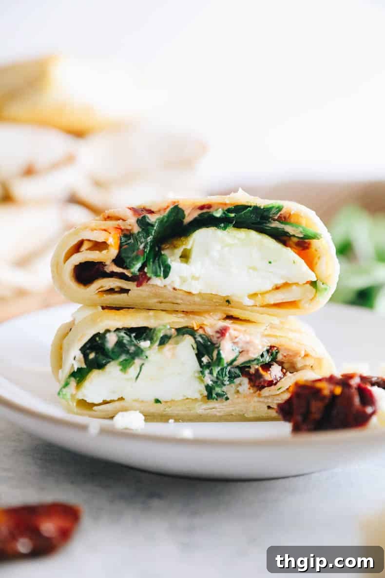 The Perfect Homemade Spinach Feta Breakfast Wrap 9 Upclose image of an egg white spinach feta wrap stacked on top of each other on a white plate, showcasing its delicious layers.