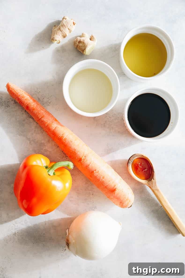 Vibrant Ginger Dressing 3 Fresh ingredients laid out on a table: carrot, bell pepper, onion, honey, ginger, avocado oil, rice wine vinegar, and tamari, ready for making ginger dressing.