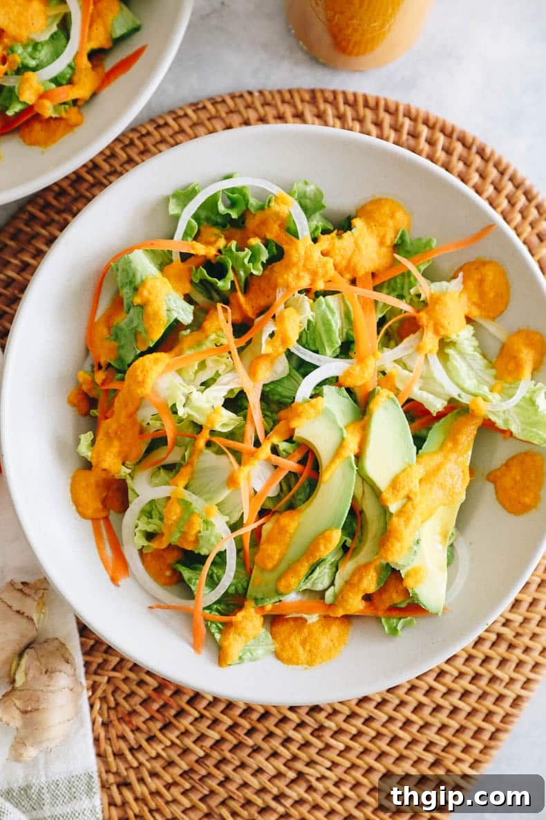 Vibrant Ginger Dressing 5 A fresh salad with lettuce, onion, carrots, and avocado in a white plate, topped with a generous drizzle of ginger dressing.