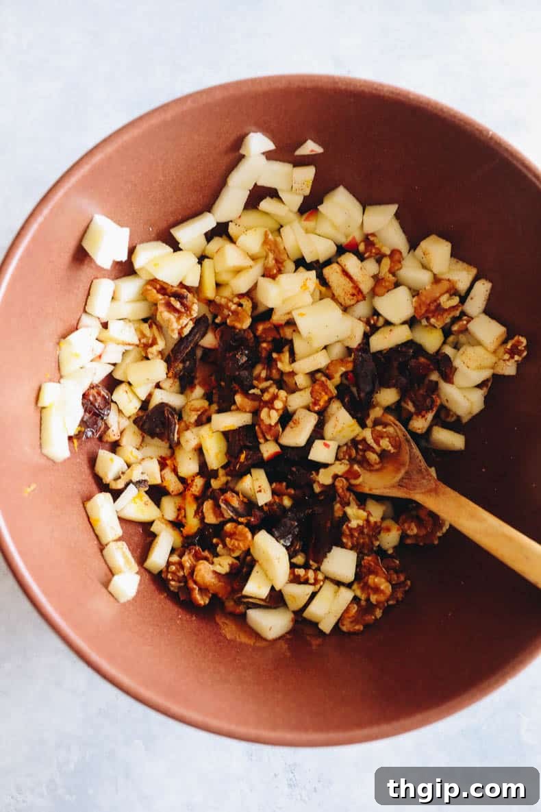 Sweet Charoset for Your Passover Seder 3 A close-up view of freshly chopped apples, dates, and walnuts in a large brown bowl, perfectly prepared and ready to be combined for Charoset.