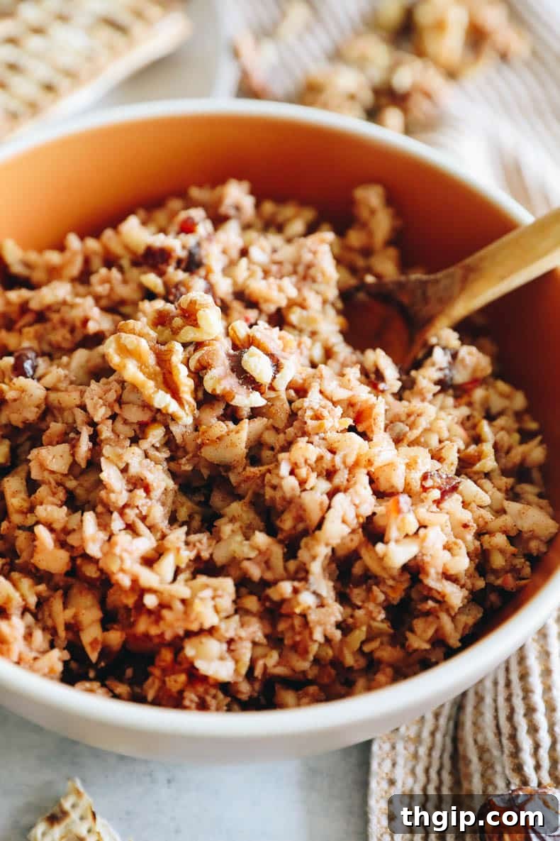 Sweet Charoset for Your Passover Seder 6 An inviting close-up of Charoset served in a charming orange bowl, accompanied by a wooden spoon, highlighting its appealing texture and rich colors.
