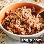 Delicious chopped apple walnut Charoset presented in a brown bowl with a wooden spoon and pieces of matzah nearby, ready to be served.