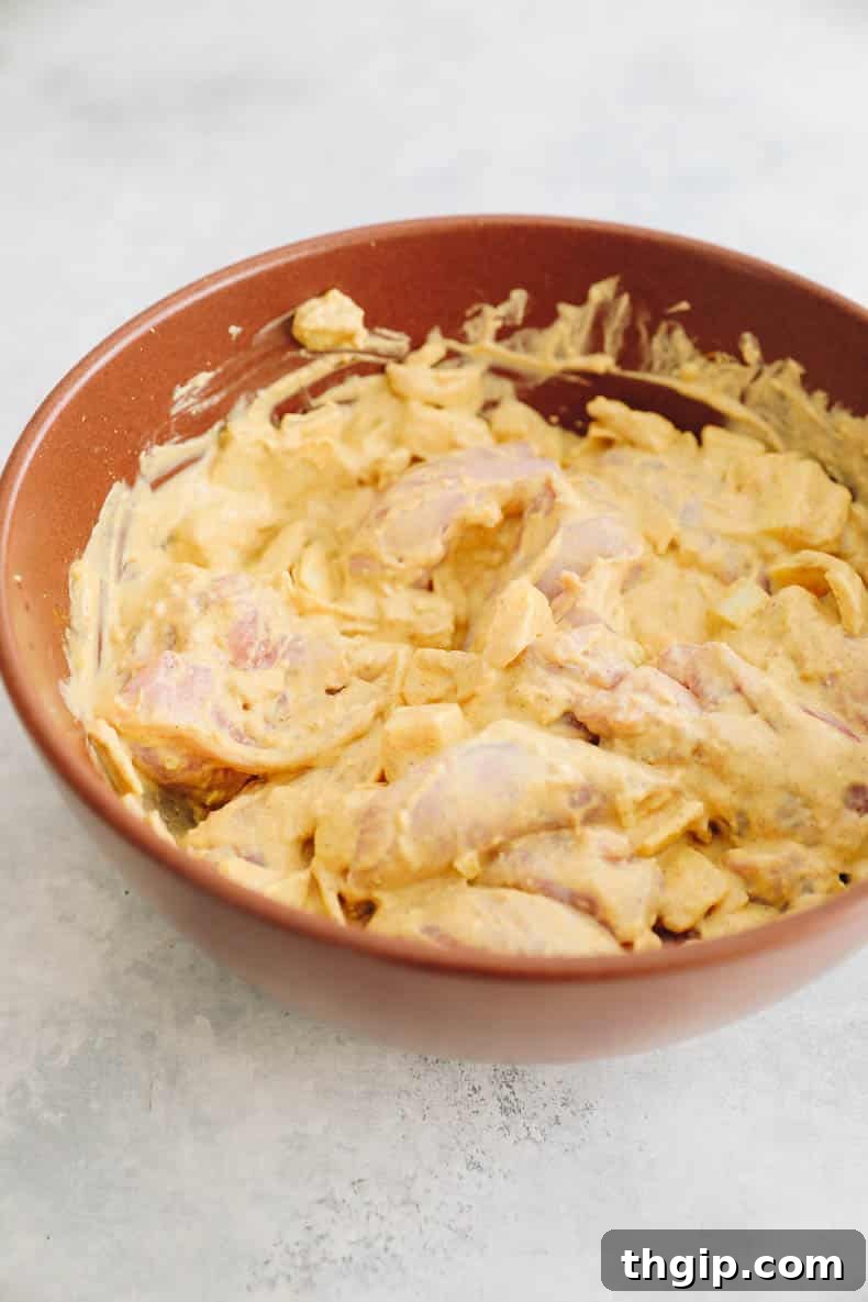 Single-Pot Tandoori Feast 3 Chicken thighs and chopped yellow onion marinating in a creamy, spice-infused Greek yogurt mixture.