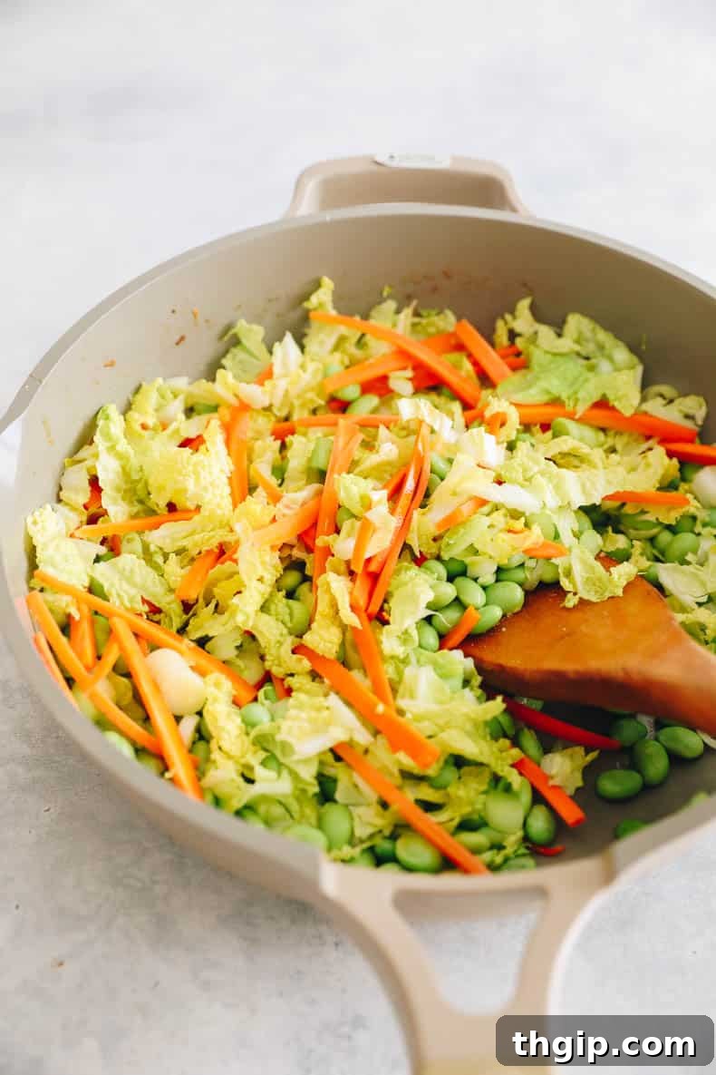 Fragrant Thai Basil Turkey Bowls 4 sliced carrots, cabbage, green onions and edamame in a skillet.
