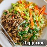 overhead of thai bowl with ground turkey, thai basil, carrots, edamame, cabbage and green onions coated with a peanut sauce.