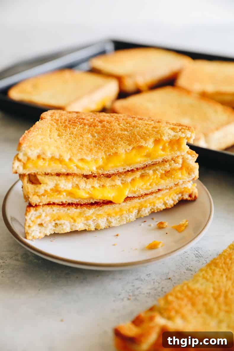 Effortless Sheet Pan Melts 2 Crispy golden oven grilled cheese sandwiches on a sheet pan, ready to be served.