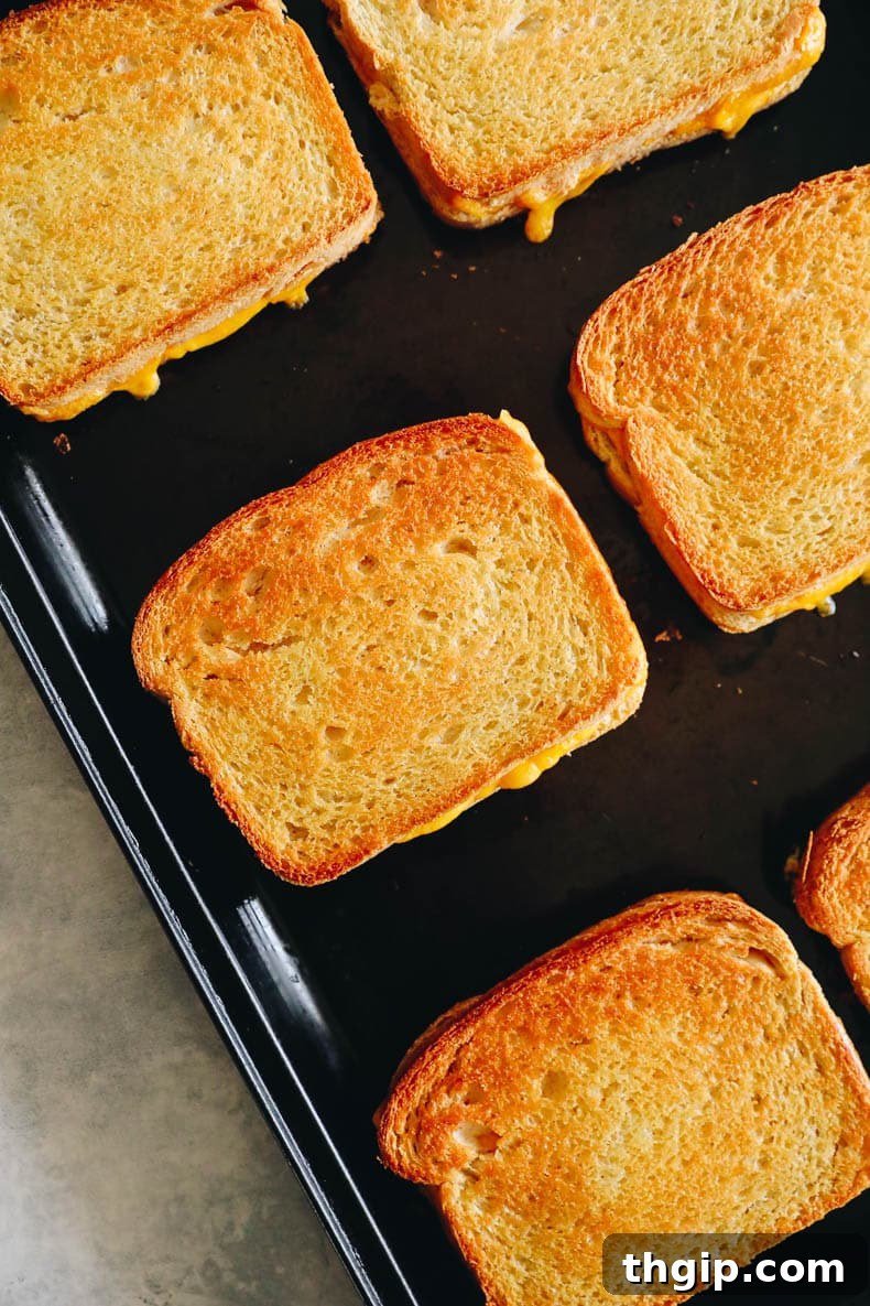 Effortless Sheet Pan Melts 3 Close-up of a stack of oven grilled cheese sandwiches, showcasing their golden crust and melted interior.