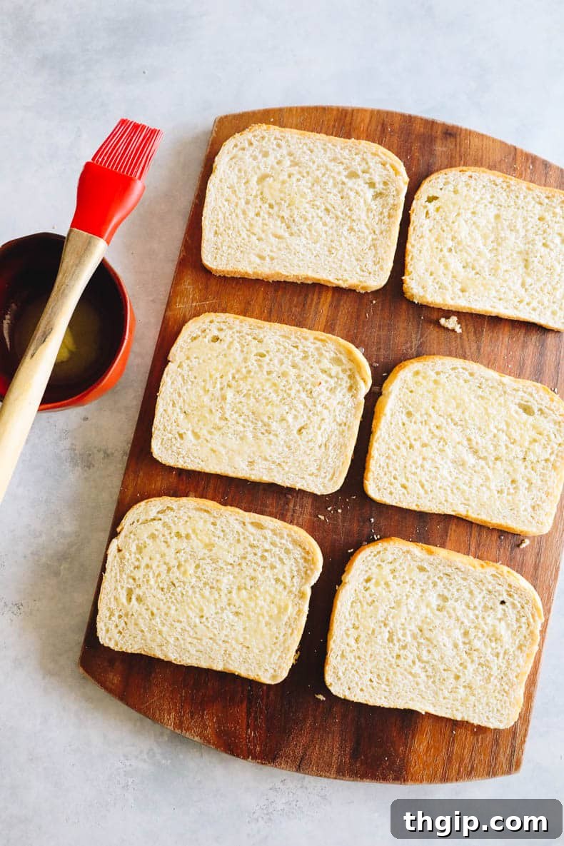 Effortless Sheet Pan Melts 4 buttered bread on a cutting board, ready for assembly