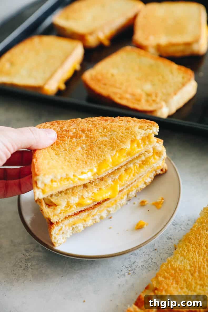 Effortless Sheet Pan Melts 8 woman's hand picking up sheet pan grilled cheese.