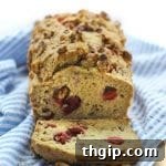 A slice of homemade Gluten-Free Cranberry Walnut Loaf, ready to be enjoyed as a healthy comfort food.