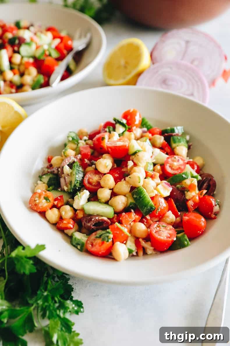 Vibrant Mediterranean Chickpea Medley 2 A close-up of a fresh Mediterranean chickpea salad with tomatoes, cucumbers, olives, and feta in a white bowl, ready to be served.