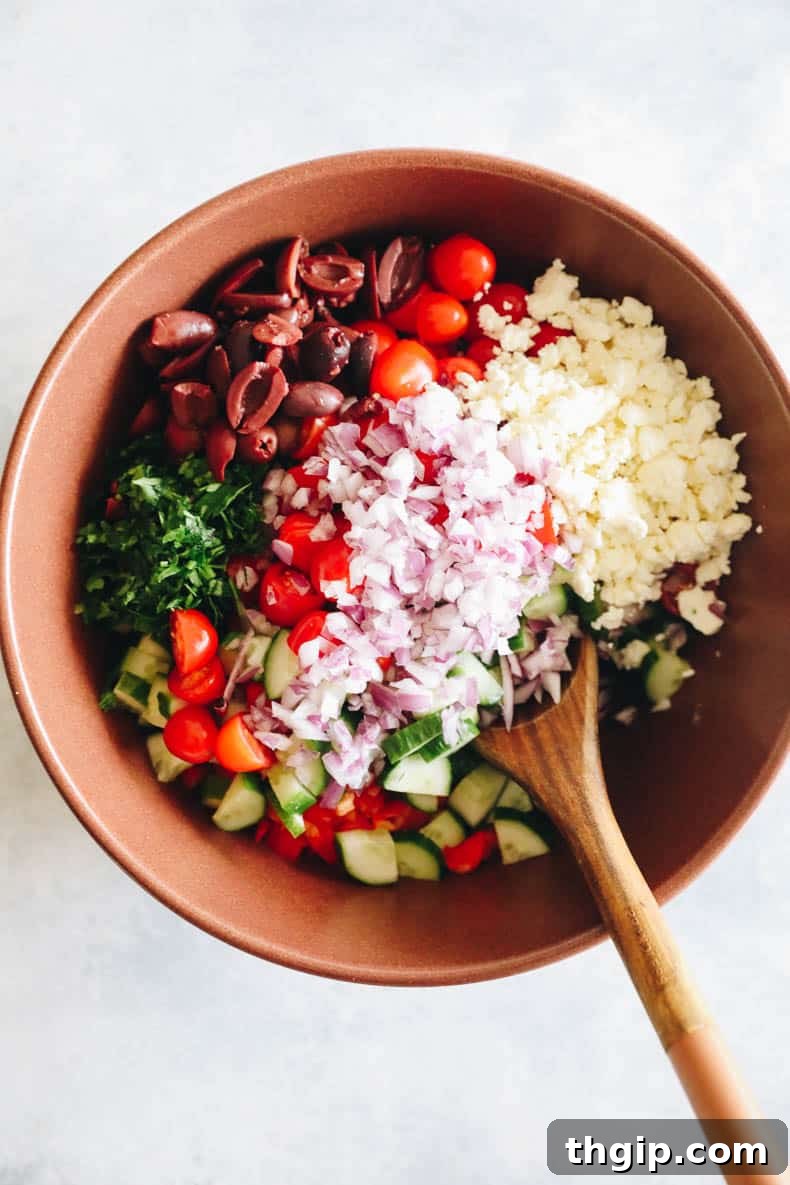 Vibrant Mediterranean Chickpea Medley 3 A collection of fresh ingredients for Mediterranean chickpea salad, including chickpeas, tomatoes, cucumbers, and herbs, arranged in a large brown bowl.
