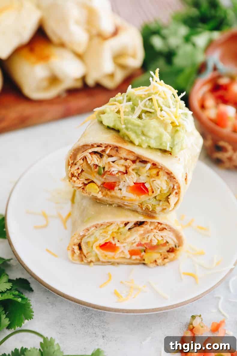 Simple Savory Chicken Burritos 11 An inviting overhead shot of delicious chicken burritos, generously topped with creamy guacamole and melted shredded cheese, ready to be served.
