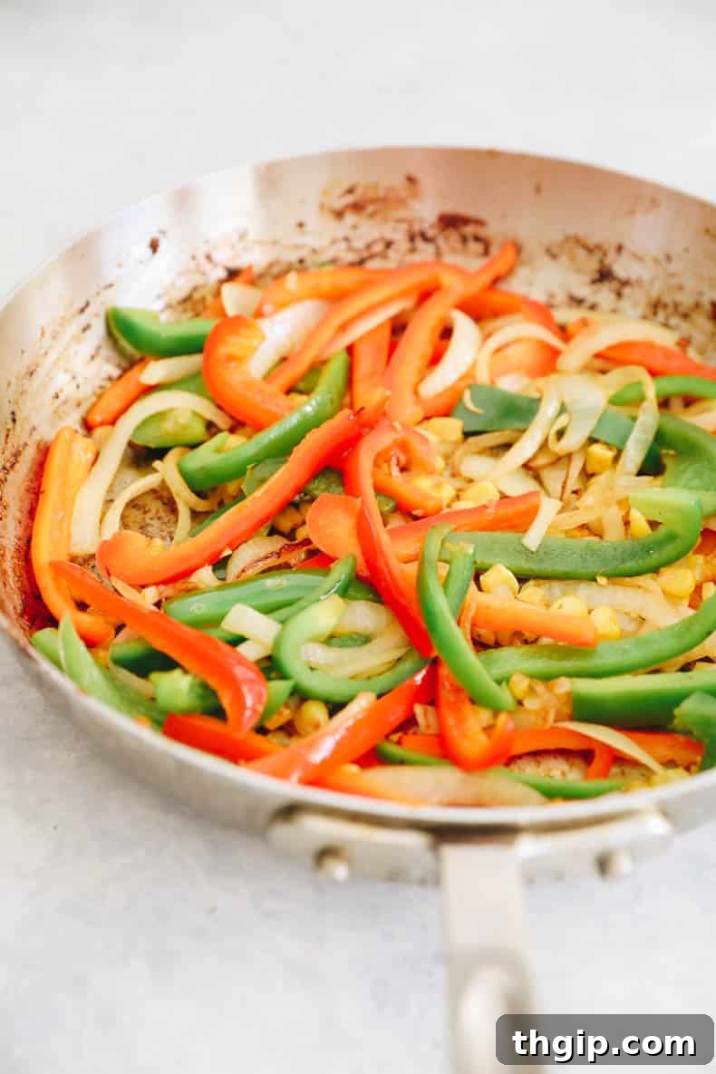 Simple Savory Chicken Burritos 4 Colorful bell peppers, onions, and corn lightly sautéed in a skillet, creating a vibrant burrito filling.