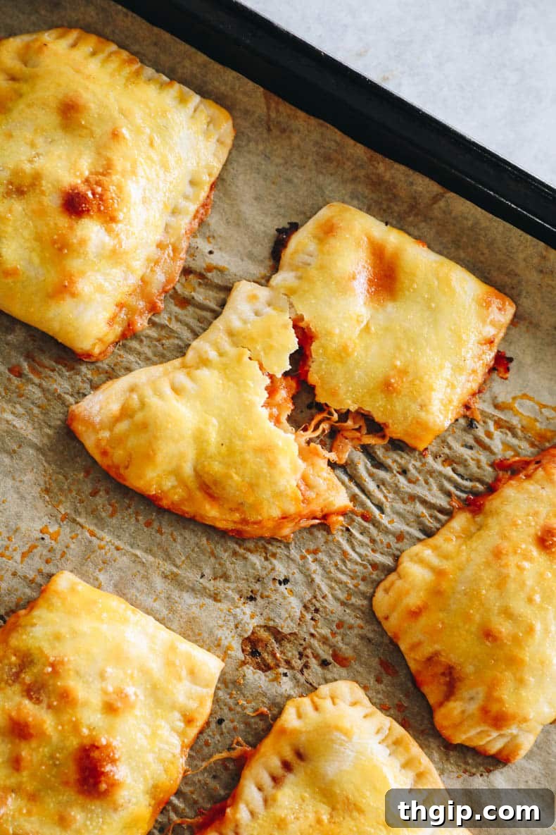 close-up of a homemade pizza pocket on a baking sheet with cheese oozing out, fresh out of the oven.