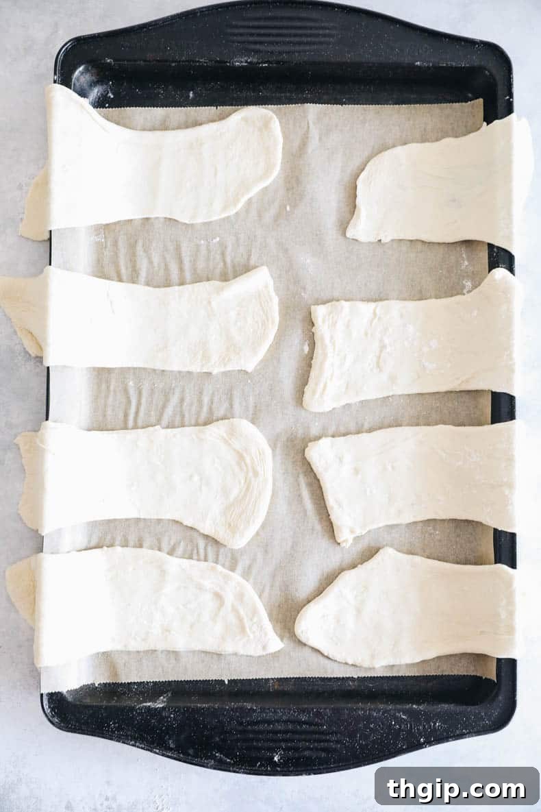 pizza dough rectangles arranged on a baking sheet, half hanging off the side.