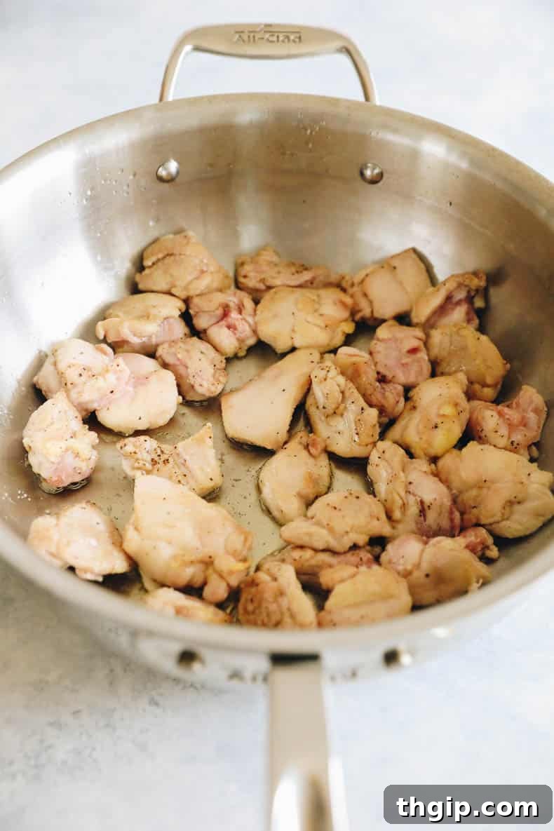 cooked chicken thighs browning in a wok.