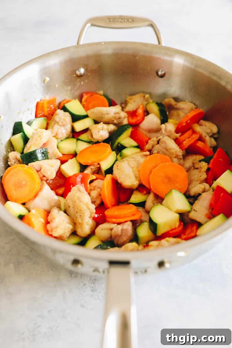 kung pao chicken and vegetables cooking together in a wok.
