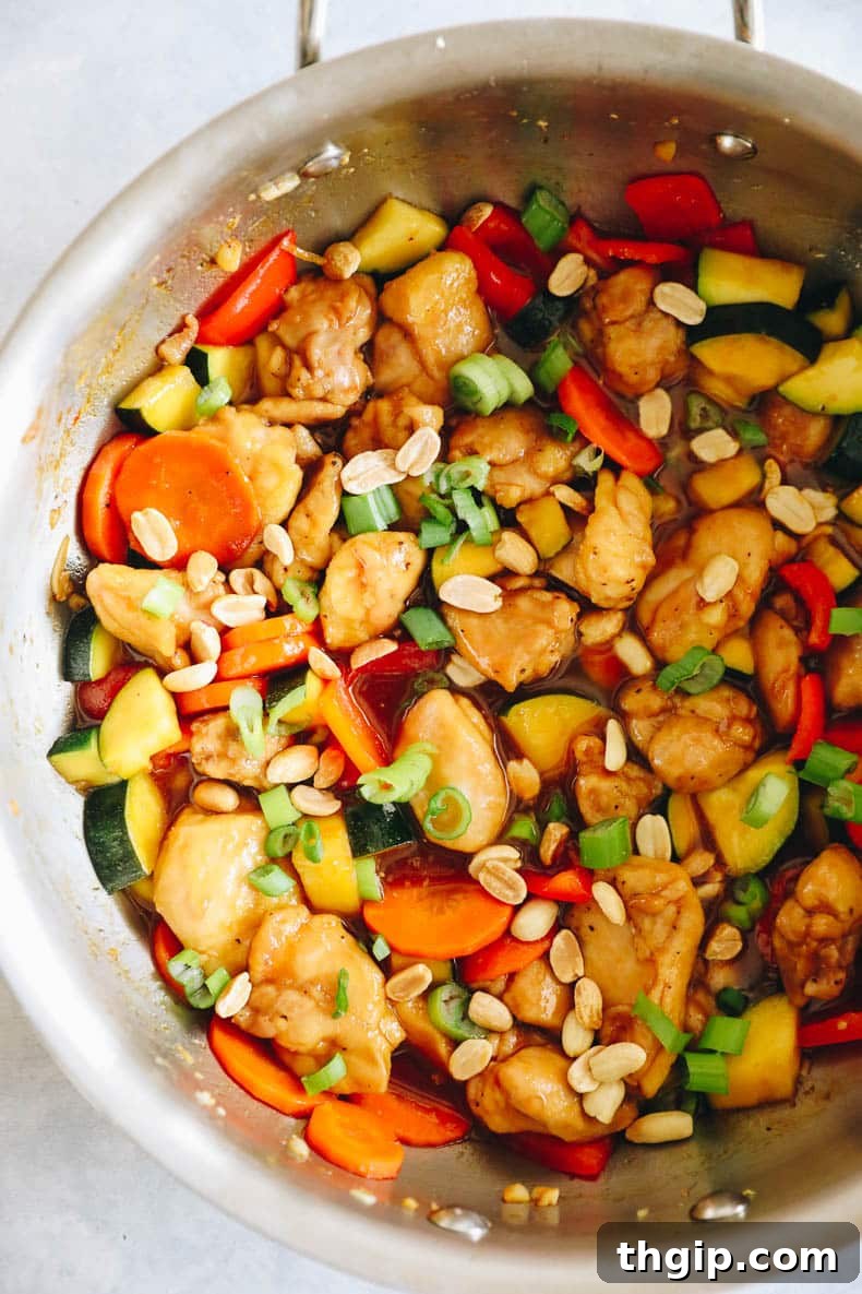 copycat panda express kung pao chicken cooked in a wok and topped with green onions and peanuts.