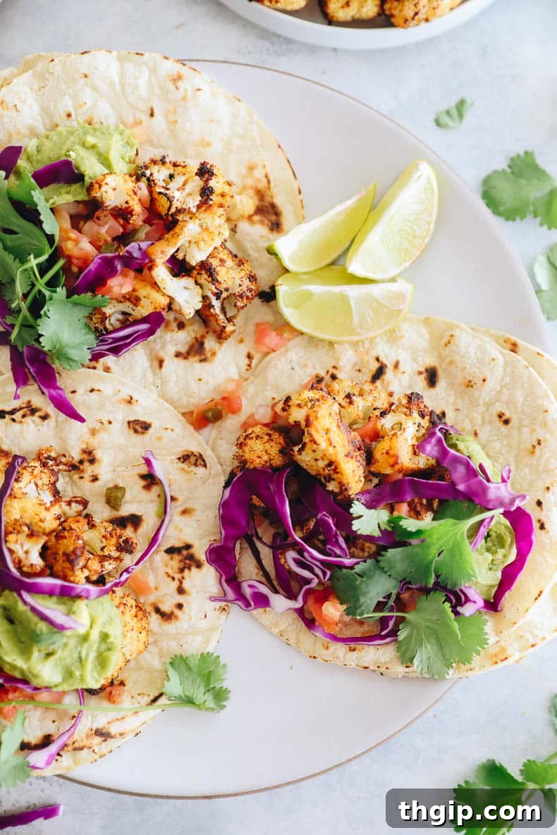 Loaded Crispy Cauliflower Tacos 6 3 cauliflower tacos on a plate with lime slices, pico de gallo, guacamole and red cabbage.