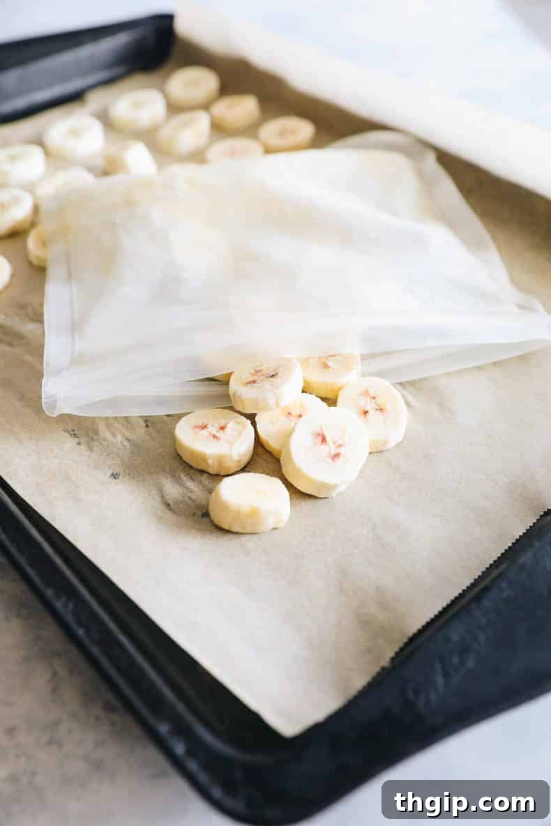 Close-up view of perfectly frozen banana coins, neatly arranged on a parchment-lined baking sheet, ready for long-term storage.