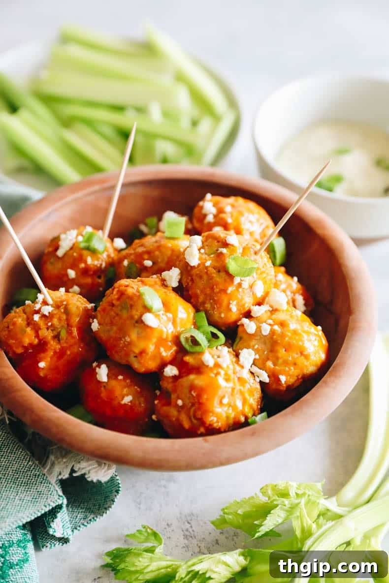 Delicious buffalo chicken meatballs served in a brown bowl with toothpicks, garnished with fresh green onions.