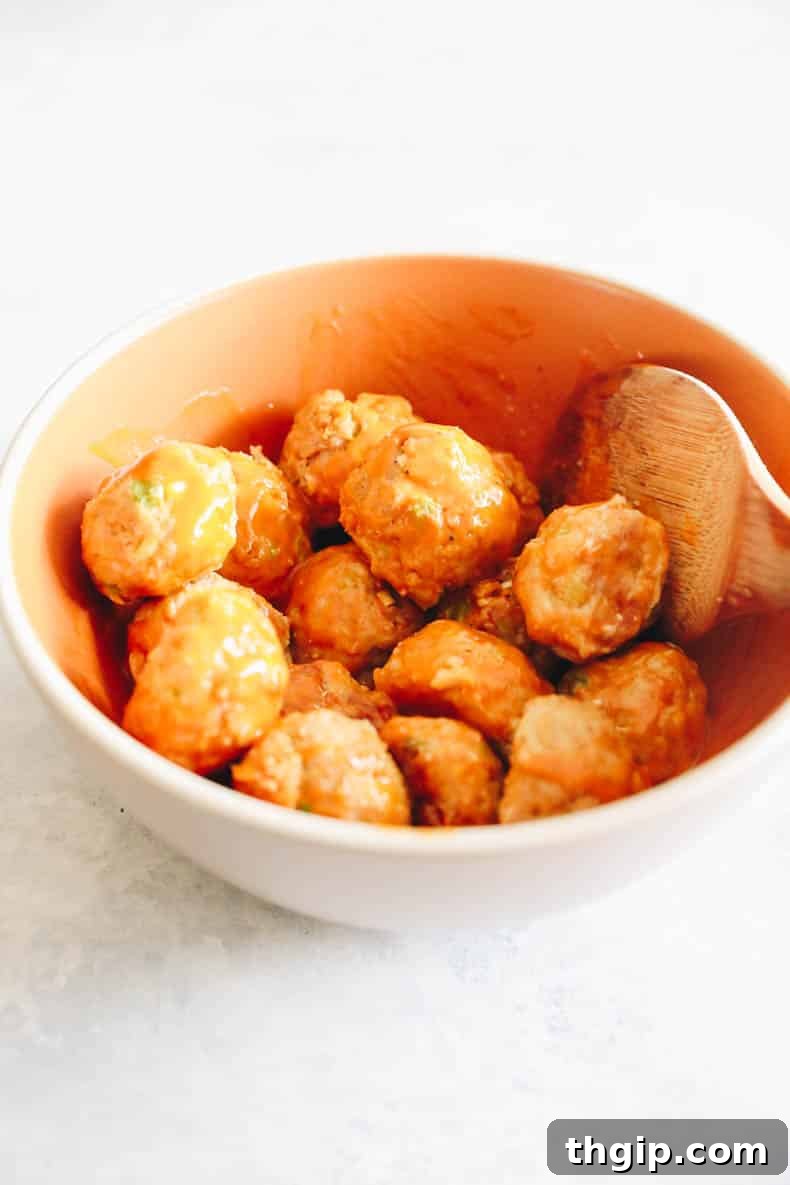 Baked chicken meatballs generously coated in buffalo sauce, ready to be served as a delicious appetizer or main course.