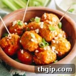 buffalo chicken meatballs in a brown bowl with toothpicks, green onions and feta cheese.