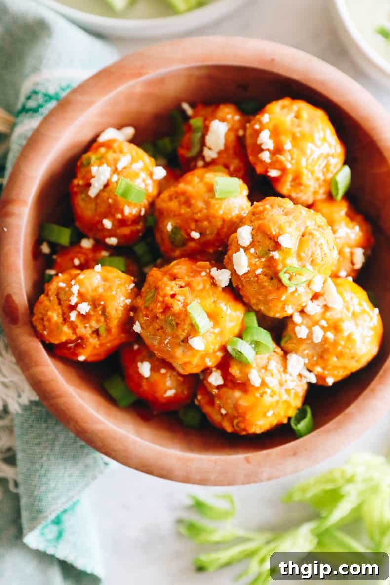 Overhead view of buffalo chicken meatballs beautifully arranged in a brown serving bowl, garnished with green onions.
