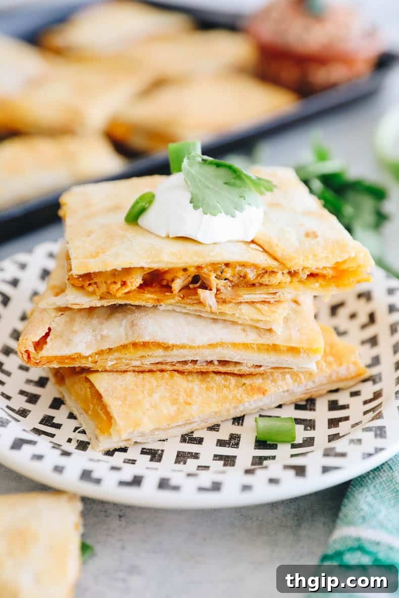 Ultimate Sheet Pan Quesadilla 7 Baked sheet pan quesadillas, freshly cut and topped with a dollop of sour cream, chopped cilantro, and sliced green onions for garnish.