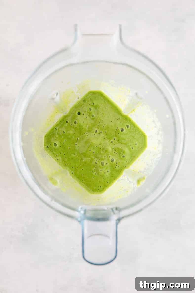 A close-up shot of a tropical kiwi smoothie being blended in a high-speed blender, creating a smooth, vibrant green liquid, ready to be poured into a glass.