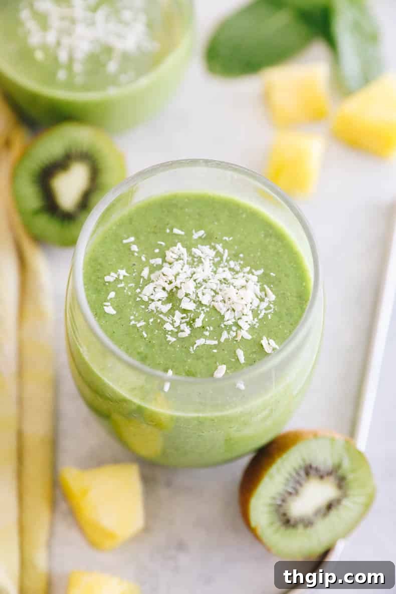 A close-up shot of a perfectly blended tropical kiwi smoothie in a clear glass, garnished with shredded coconut, highlighting its vibrant green color and inviting texture.