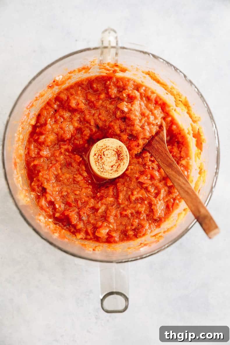 The vibrant red sofritas sauce paste in a food processor, ready to be cooked.
