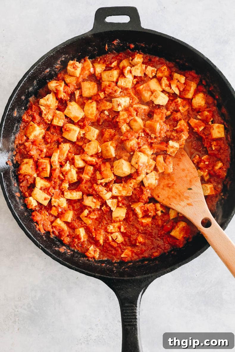 Cooked chipotle sofritas simmering in a cast iron skillet, coated in the rich, dark sauce.