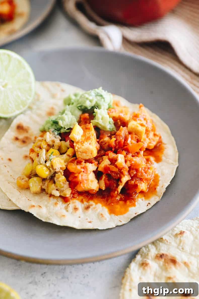 Vegan chipotle sofritas served on a warm corn tortilla with fresh guacamole and corn salsa.