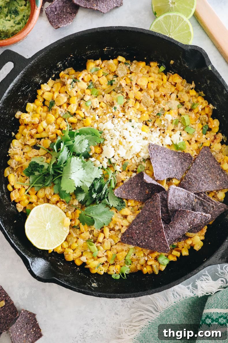 Creamy Elote Dip 2 Mexican Street Corn Dip in a cast iron skillet, garnished with fresh cilantro and lime wedges.