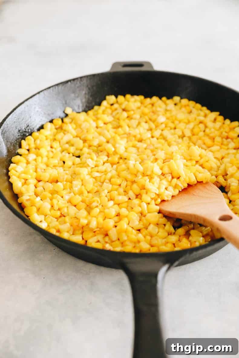 Creamy Elote Dip 3 Cooked corn kernels browning in a cast iron skillet with melted butter.