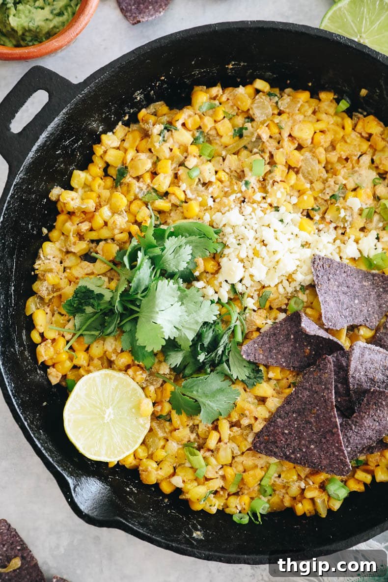 Creamy Elote Dip 6 Overhead view of Mexican street corn salad served in a cast iron skillet, garnished with fresh herbs and lime.