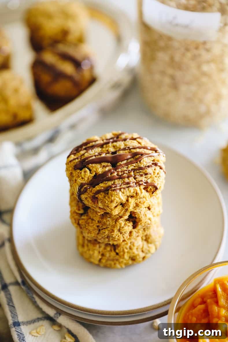 Angled shot of stacked pumpkin breakfast cookies drizzled with chocolate.