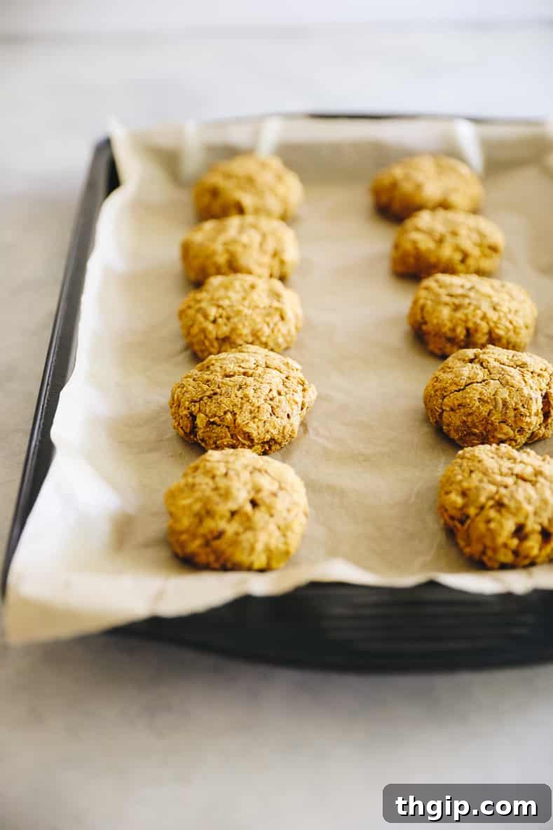 Sheet pan lined with parchment paper and topped with pumpkin breakfast cookies.
