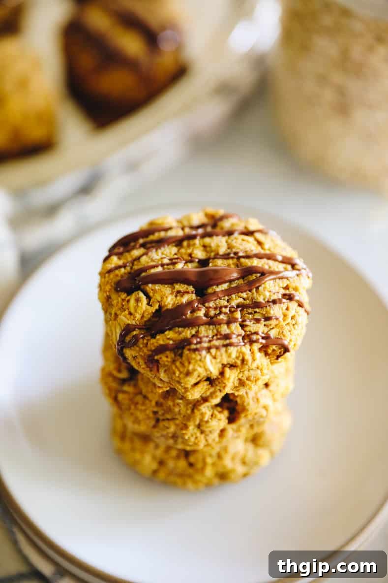 Angled shot of stacked pumpkin breakfast cookies drizzled with chocolate.