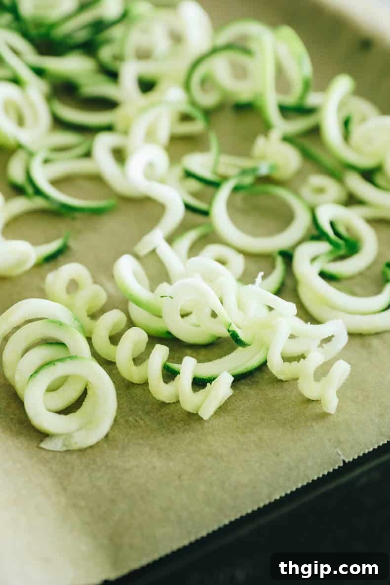 Maximize Your Zucchini Harvest: Freezing Made Easy 11 Delicate zucchini noodles spread out in a single layer on a parchment-lined baking sheet, preparing for flash freezing.