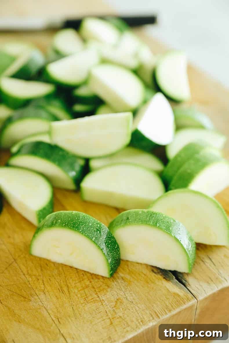 Maximize Your Zucchini Harvest: Freezing Made Easy 3 Fresh zucchini expertly chopped into uniform half-moon shapes, ready for the blanching process on a clean cutting board.
