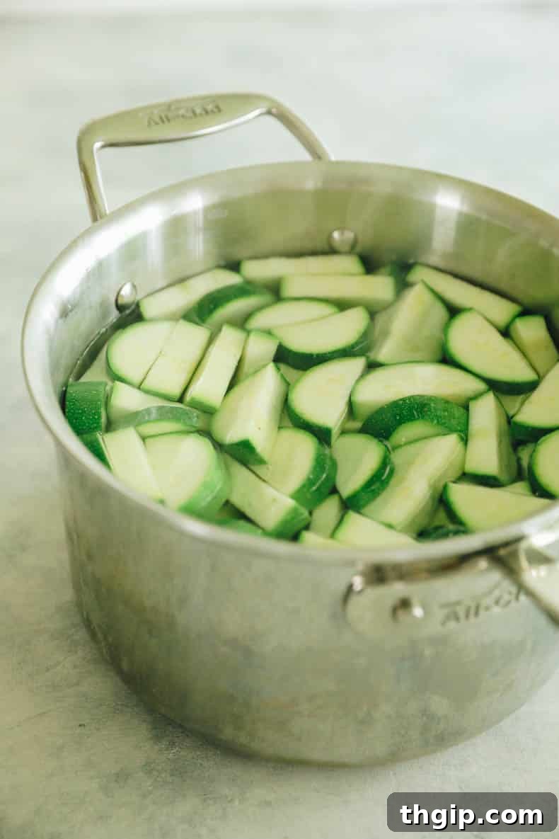 Maximize Your Zucchini Harvest: Freezing Made Easy 4 Bright green zucchini pieces submerged in a pot of vigorously boiling water, undergoing the crucial blanching process.