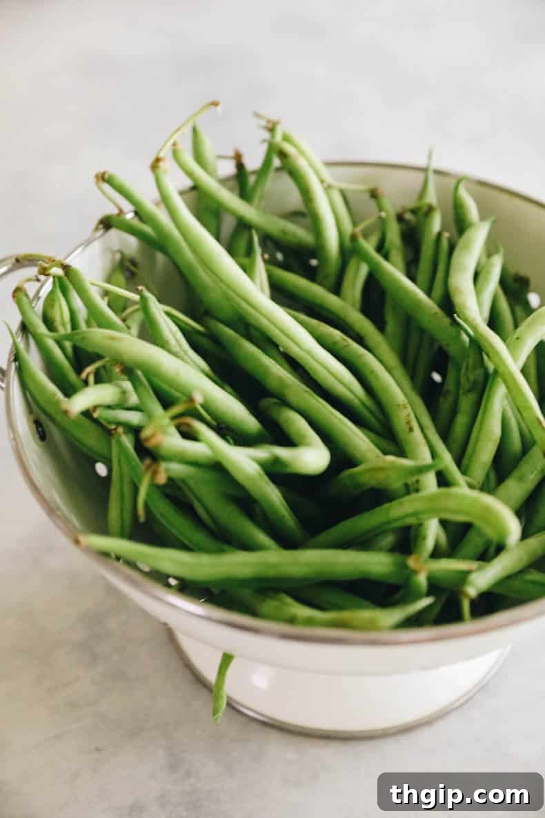 Freshly washed green beans draining in a colander, showcasing their vibrant green color before preparation.