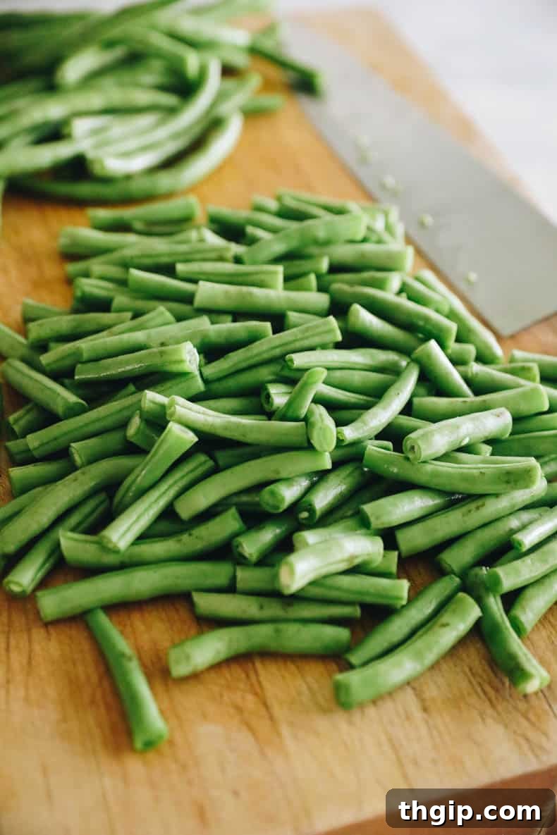 Fresh green beans meticulously cut into uniform 1-inch pieces on a cutting board, neatly arranged and prepared for freezing.