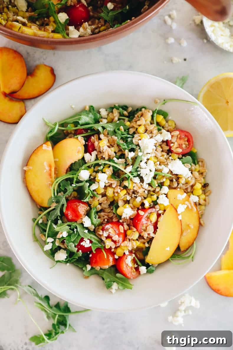 Vibrant Summer Farro Bowl 2 A refreshing summer farro salad in a crisp white bowl, showcasing vibrant corn, juicy tomatoes, sweet peaches, and crumbled feta cheese, all tossed in a zesty lemon vinaigrette. Perfect for healthy summer eating.